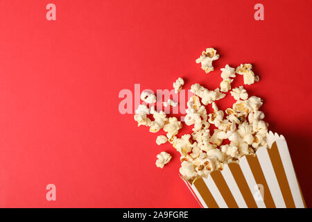 Flat lay composition with striped box and popcorn on color background Stock Photo