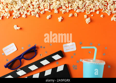 Flat lay. Popcorn, clapperboard, 3d glasses, drink and tickets on orange background, copy space Stock Photo