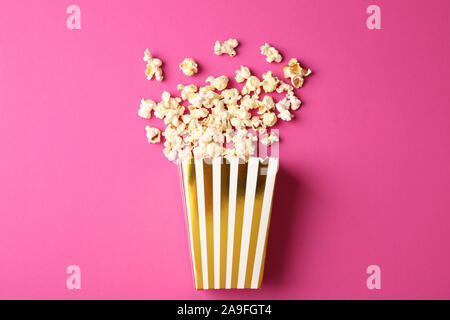 Flat lay composition with striped box and popcorn on color background Stock Photo