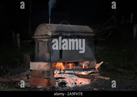 cooking smoked meats in a mobile metal smokehouse at the stake Stock Photo