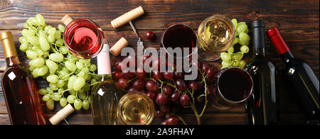 Flat lay. Grapes, corkscrew, bottles and glasses with wine on wooden background Stock Photo