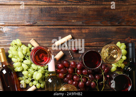 Flat lay. Grapes, corkscrew, bottles and glasses with wine on wooden table, copy space Stock Photo