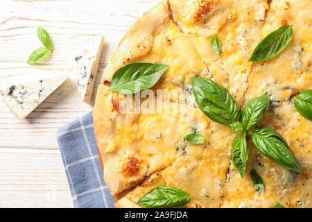 Cheese pieces and pizza with basil on white background, close up Stock Photo