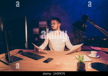 Photo of thoughtful pensive bearded focused man analyzing information received from several sources and trying to make up report sitting at desktop Stock Photo
