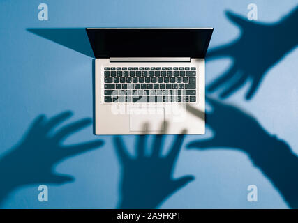 Threatening hands attacking a laptop and stealing information: cyber crime, hackers and malware concept Stock Photo
