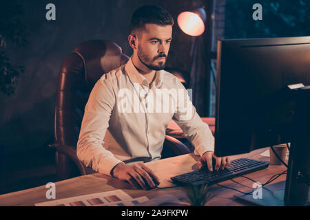 Photo of serious confident clever businessman working at night shift developing his project eliminating all disadvantages of it by using computer Stock Photo