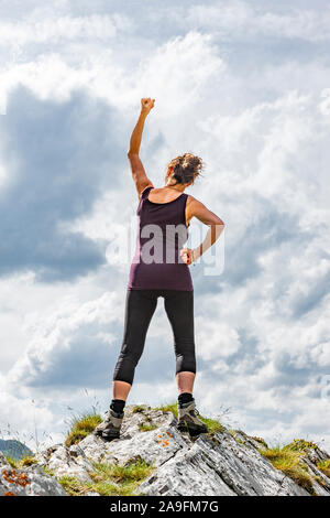 Woman in victory pose on a mountain peak Stock Photo