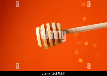 Dipper with honey against orange background with blurred lights, copy space Stock Photo