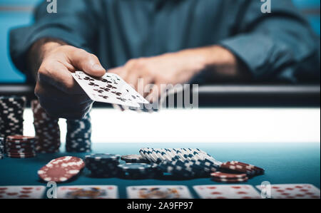 Man playing Texas Hold 'em poker at Casino, he is holding two cards Stock Photo