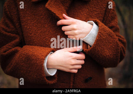 Unrecognizable  female hands in bright  brown coat in autumn Stock Photo