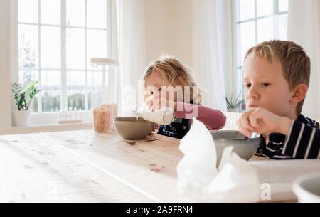 brother and sister eating breakfast at home before school Stock Photo