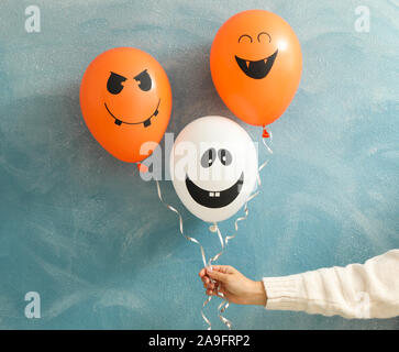 Female hand holding halloween balloons on color background Stock Photo