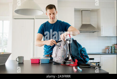 father packing his kids school bags in the morning at home Stock Photo