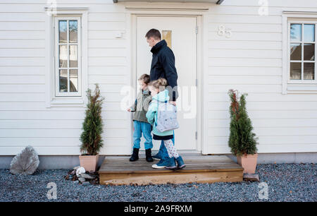 father taking his kids to school locking the front door at home Stock Photo
