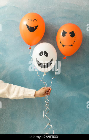 Female hand holding halloween balloons on color background Stock Photo