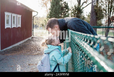 father kissing his daughter goodbye at the school gate Stock Photo