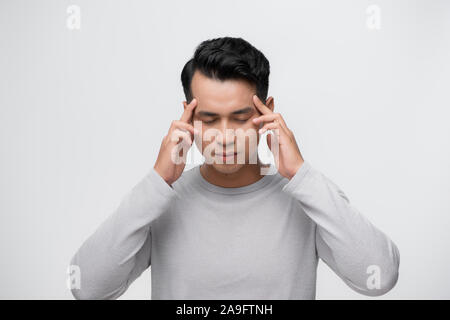 Young Asian man having a headache. Concept of stress and overworking. An isolated portrait Stock Photo