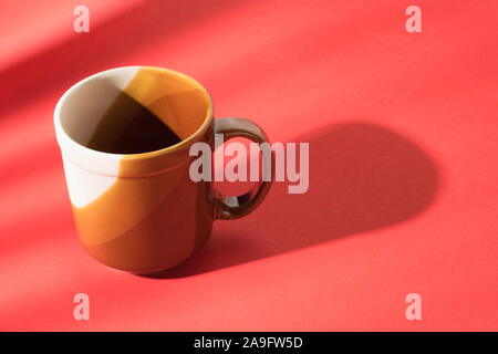 Empty brown cup on red table. Abstract coffee theme still life Stock Photo