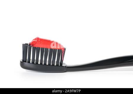 Black toothbrush with red toothpaste close up, Isolated on white background Stock Photo