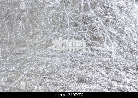 Crumpled silver foil texture. Sheet of rough metal decorative material. Shiny abstract backdrop. Stock Photo