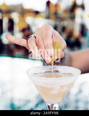 Female bartender is squeezing orange juice into glass, toned Stock Photo