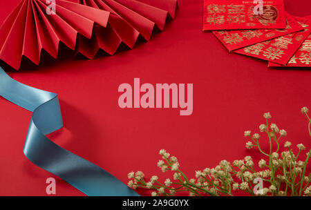 The red background of Chinese New Year's theme, with red folding fan and lucky money, Floret and blue belt，translation：may prosperity be with you Stock Photo