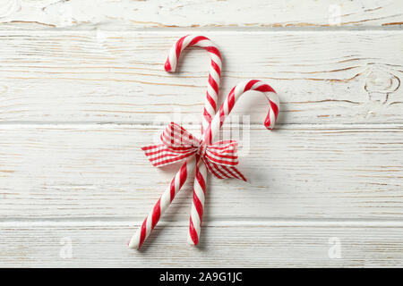 Sweet candy canes with bows on white wooden background, space for text Stock Photo