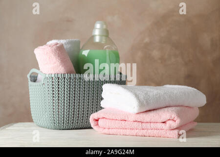 Basket with clean towels and laundry liquid on wooden background, space for text Stock Photo