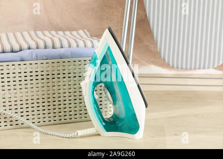 Iron and basket with laundry against brown background, space for text Stock Photo