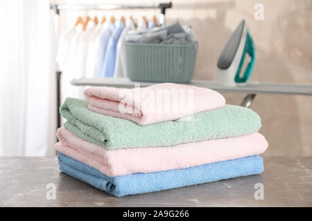 Stack of clean towels on ironing board, space for text Stock Photo