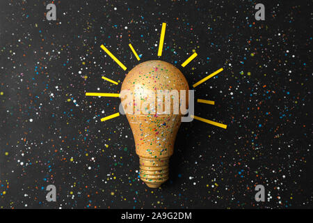 Paint splatters and spots on light bulb and black background. Creative idea concept Stock Photo