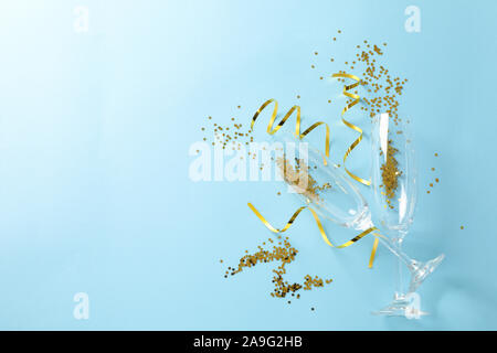 Champagne glasses with glitter on blue background, space for text Stock Photo