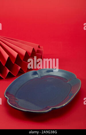 Chinese style red background and red folding fan and dark blue long plate Stock Photo