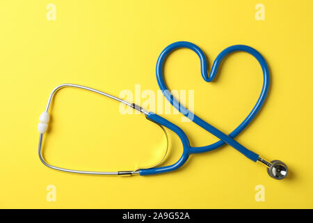 Stethoscope on yellow background, top view and space for text
