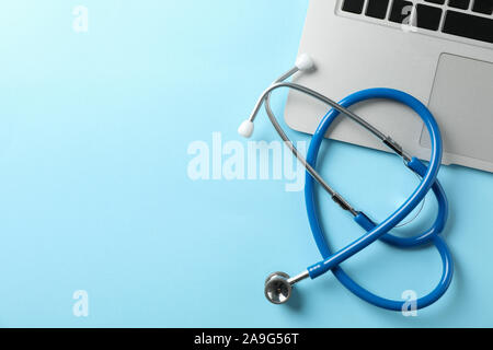 Stethoscope and laptop on blue background, space for text Stock Photo