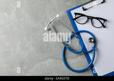 Stethoscope, tablet and glasses on grey background, copy space Stock Photo