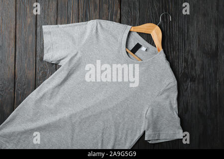 Hanger with blank gray t-shirt on wooden background, space for text Stock Photo