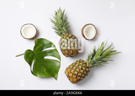 Pineapples, coconuts and palm leaves on white background, top view Stock Photo