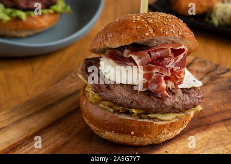 Homemade hamburger with straw potatoes, fried egg and Guijuelo ham on a wooden cutting board Stock Photo