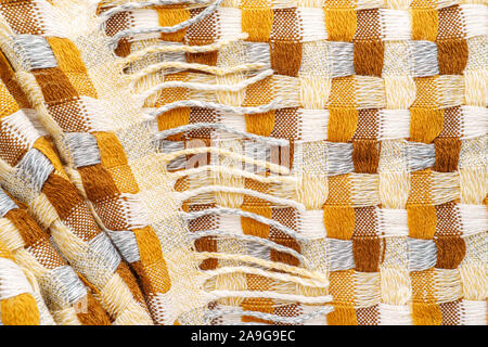Knitted Plaid with Fringe Background. Knitwear Blanket Fabric Texture with a Complex Square Interweaving. Stock Photo
