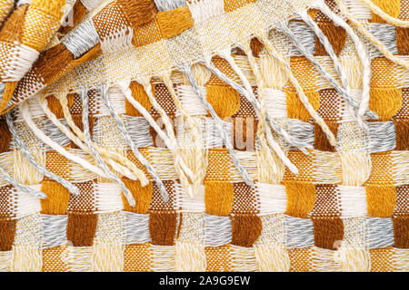 Knitted Plaid with Fringe Background. Knitwear Blanket Fabric Texture with a Complex Square Interweaving. Stock Photo