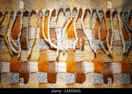 Knitted Plaid with Fringe Background. Knitwear Blanket Fabric Texture with a Complex Square Interweaving. Stock Photo