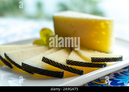 Spanish sheep cheese served with white grapes on andalusian style table outside with sea view Stock Photo