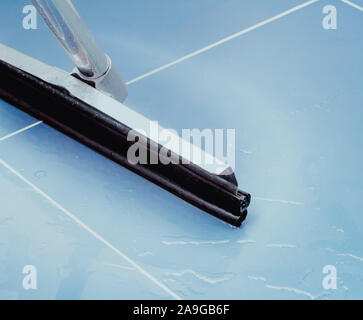 Photo of a floor squeegee in the blue floor bathroom. Stock Photo