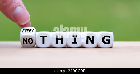 Hand turns a dice and changes the word 'nothing' to 'everything'. Stock Photo