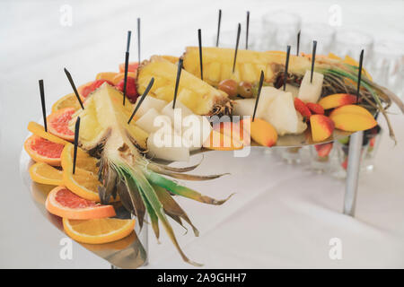 A beautiful platter of fruits, namely: pineapples, oranges, grapefruit, strawberries, grapes, melon, peaches. Fruit and berry canapes on skewers look Stock Photo
