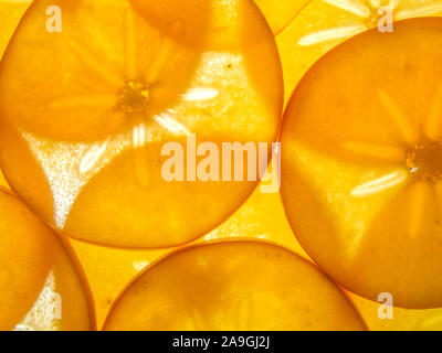 background of back lit ripe kaki persimon slices arranged Stock Photo