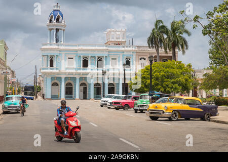 Cienfuegos, Cuba - July 28, 2018; typical colorful Cuban oldtimer classic cars in famous Palatul Ferrer Park Casa provincială de cultură in background Stock Photo
