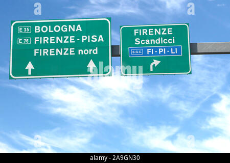road signs of the Italian highway with the localities of Florence Bologna Pisa and blue sky in the background Stock Photo
