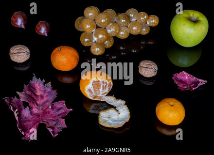 Beautiful composition of autumnal fruit and leaves on a shiny black background with reflection Stock Photo